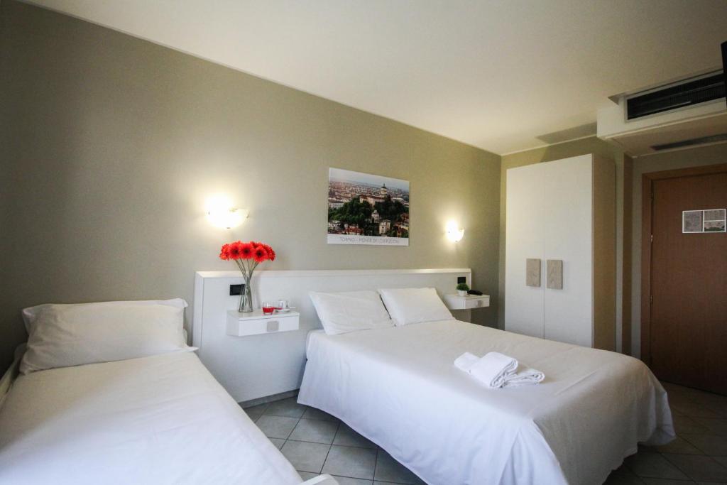 坎迪奥洛Green Class Hotel Candiolo的配有白色床单的酒店客房内的两张床