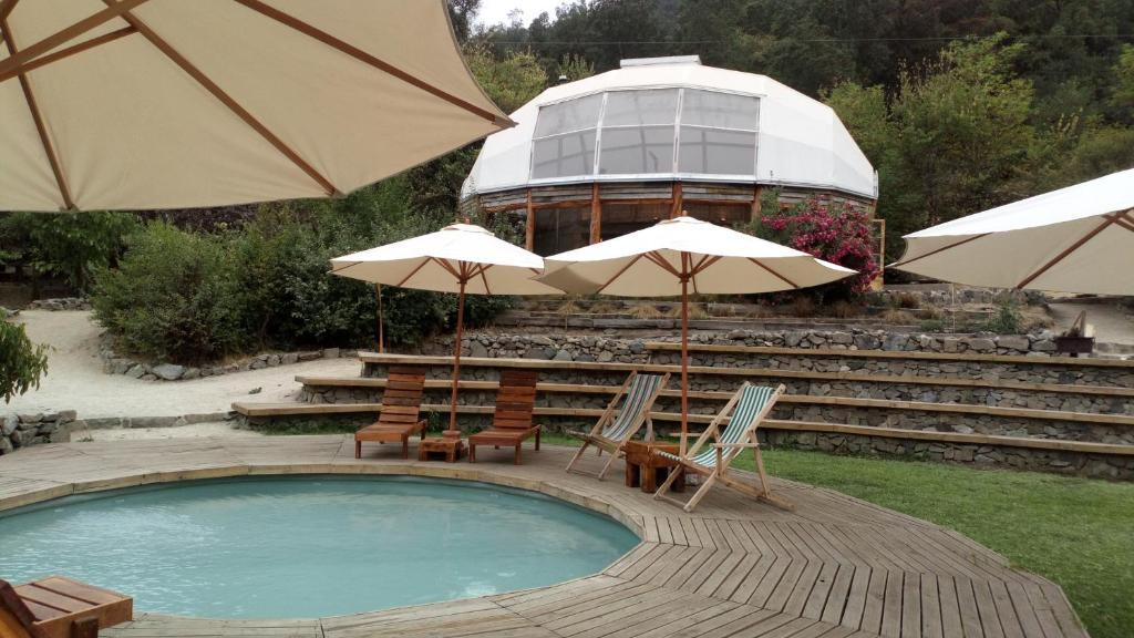 奥尔穆埃Biosfera Lodge的一个带椅子和遮阳伞的游泳池和一座建筑