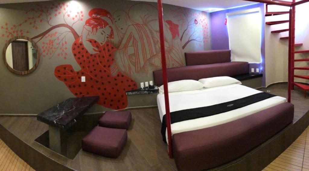 库埃纳瓦卡Motel Tatami的卧室配有一张床,墙上挂有绘画作品