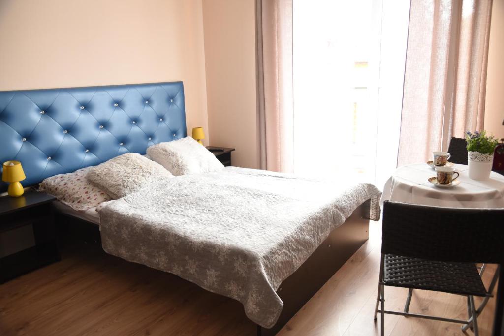 姆热日诺Nestor II的一间卧室配有一张带蓝色床头板的床和一张桌子