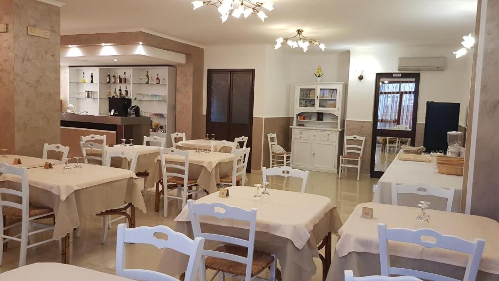 切萨雷奥港阿尔伯格普利玛维拉旅馆的一间带白色桌椅的餐厅和一间厨房