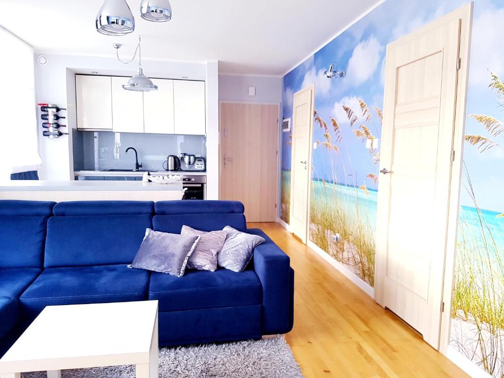 加茨比亚格拉ApartMorze apartamenty Fregata的一间带蓝色沙发的客厅和一间厨房