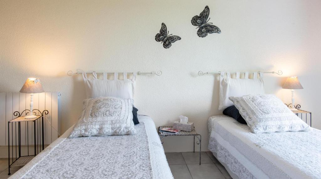 Port-Sainte-Marie拉洛奇尼尔住宿加早餐旅馆的卧室内的两张床,墙上有蝴蝶