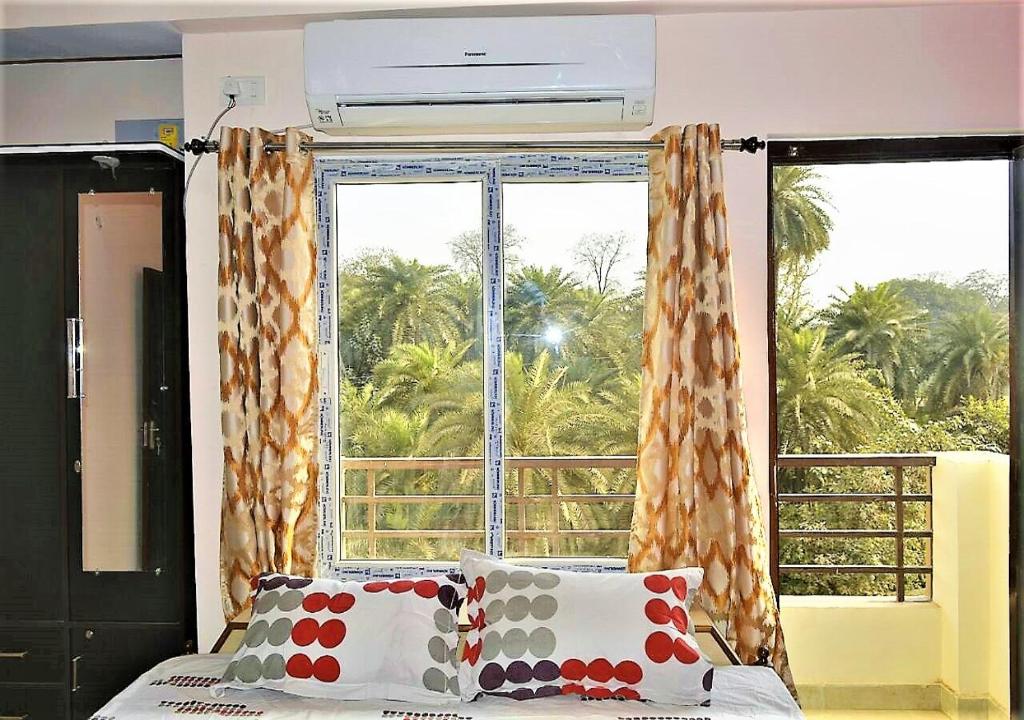瓦拉纳西Pretty Garden View Apartment 3BHK Furnished Flat near Kashi Vishwanath Temple的一间卧室设有一张床和一个大窗户