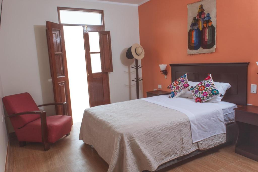 阿亚库乔Hospedaje Zaragoza的一间卧室配有一张床和一张红色椅子