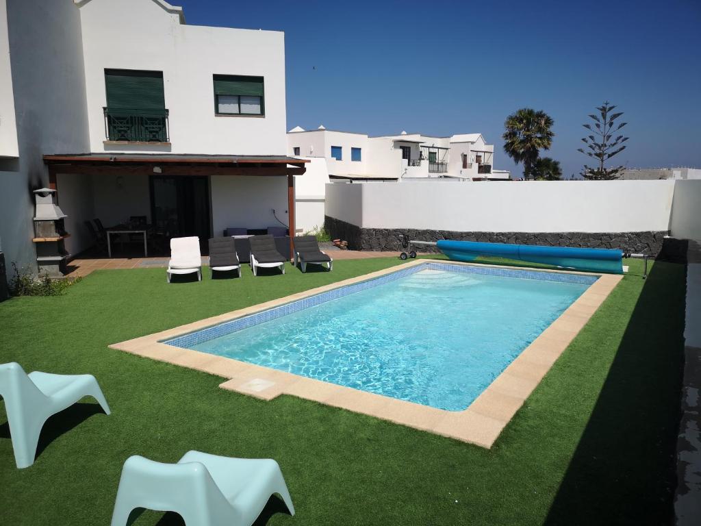 普拉亚布兰卡VillaAntonia private huge heated pool and super fast wifi的一个带椅子的游泳池以及一座房子
