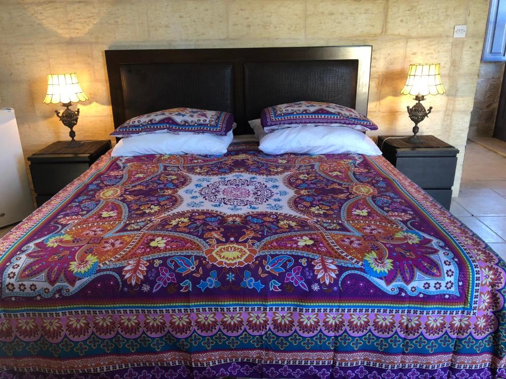 MġarrTa Skorba Farmhouse Mgarr的床上有色彩缤纷的毯子和枕头