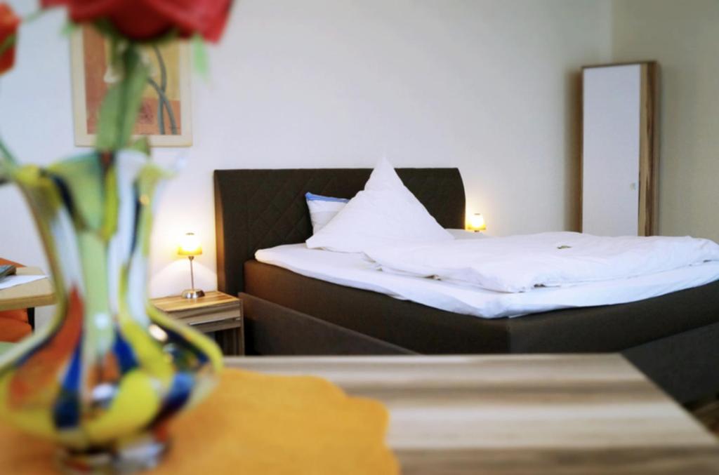 伦格里希Hotel-Cafe Maxx的一间卧室配有一张床,一个花瓶摆放在桌子上
