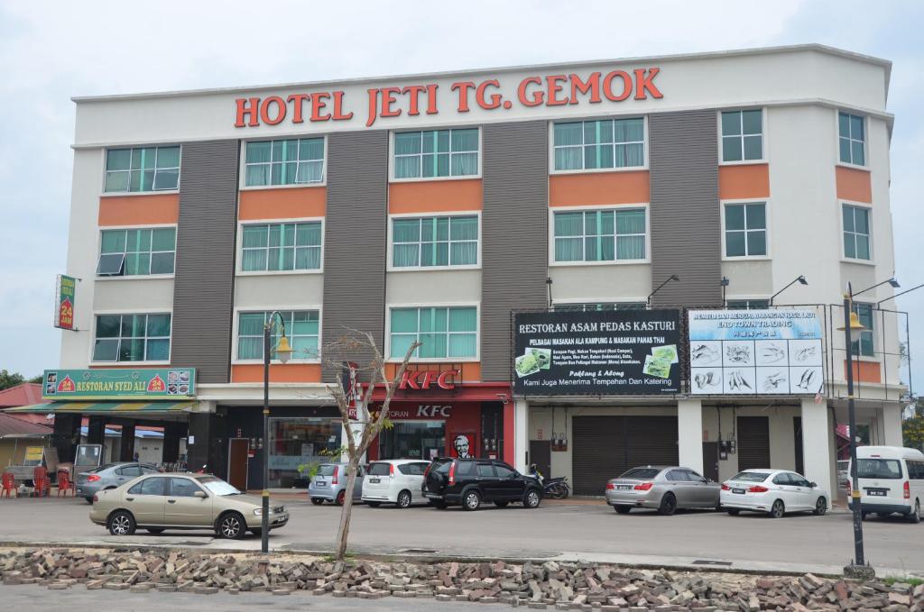 Padang EndauHotel Jeti Tg Gemok的酒店前方设有停车场,是一座独具风格的大楼。