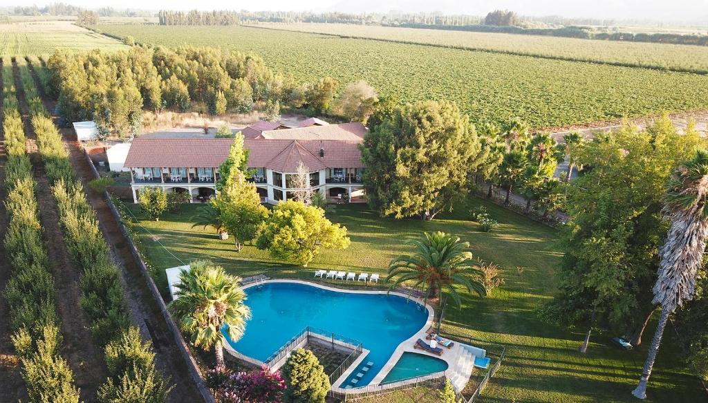 圣克鲁兹La Perla Hotel的享有带游泳池和田野的房屋的空中景致