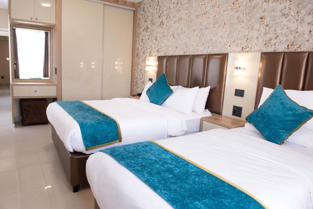 德班Britannia Hotel的两张位于酒店客房的床,配有蓝色枕头
