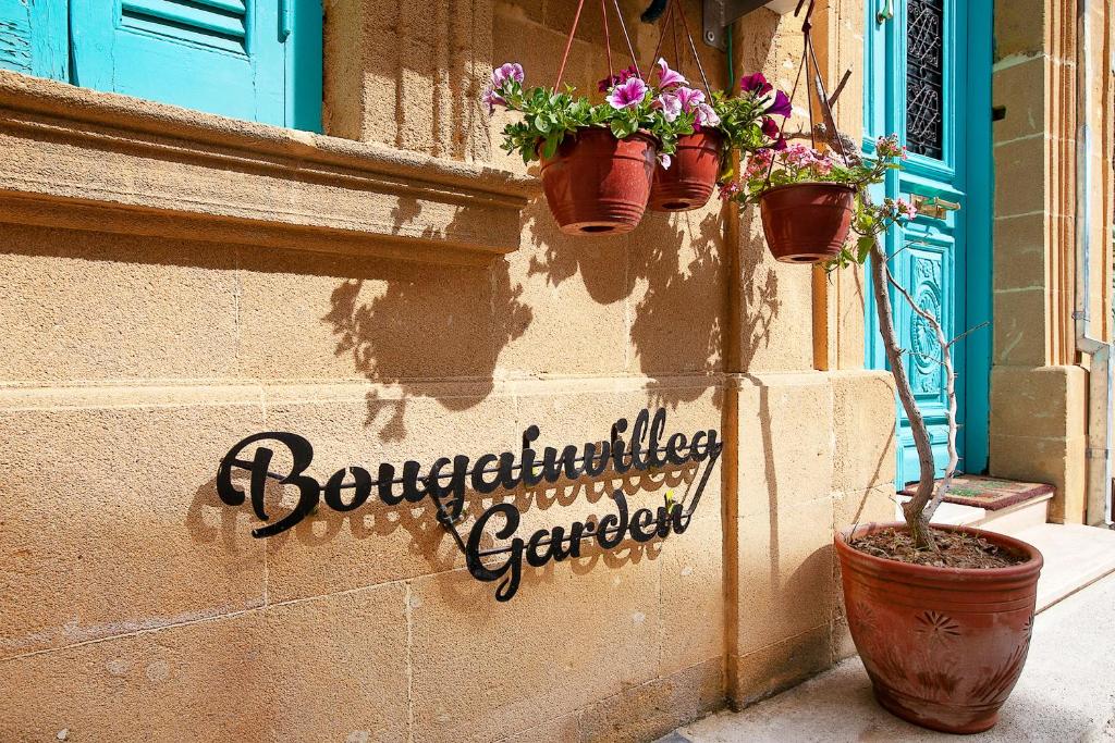 北尼科西亚Bougainvillea Garden的建筑边有盆栽植物的标志