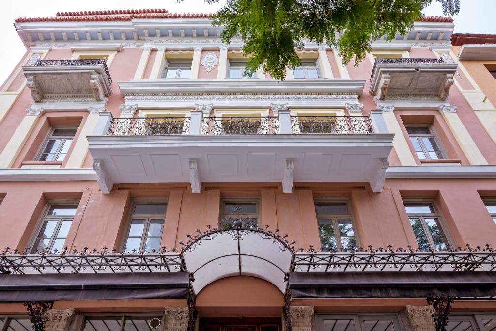 雅典埃姆帕里康雅典酒店的粉红色的建筑设有阳台和阳台