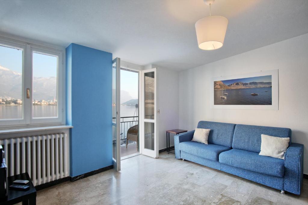 瓦尔玛德雷拉COZY LAKE COMO APARTMENTS的客厅设有蓝色的沙发和窗户。