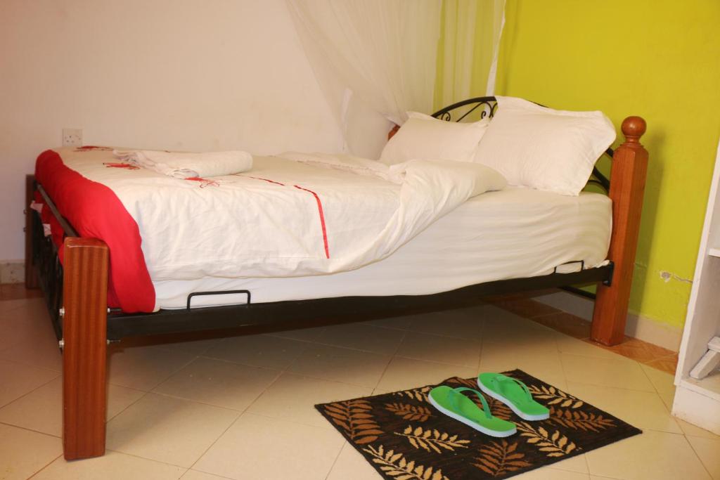 KisiiPreston Pointe Resort的一张小床,地板上配有绿拖鞋