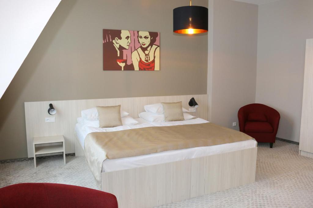 布拉格1共和国酒店的一间卧室配有一张大床和一张红色椅子