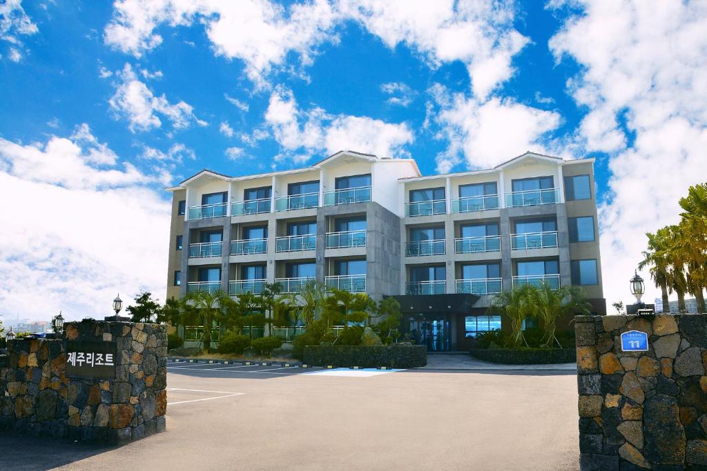 济州市济州岛度假酒店的一座白色的大建筑,前面有棕榈树