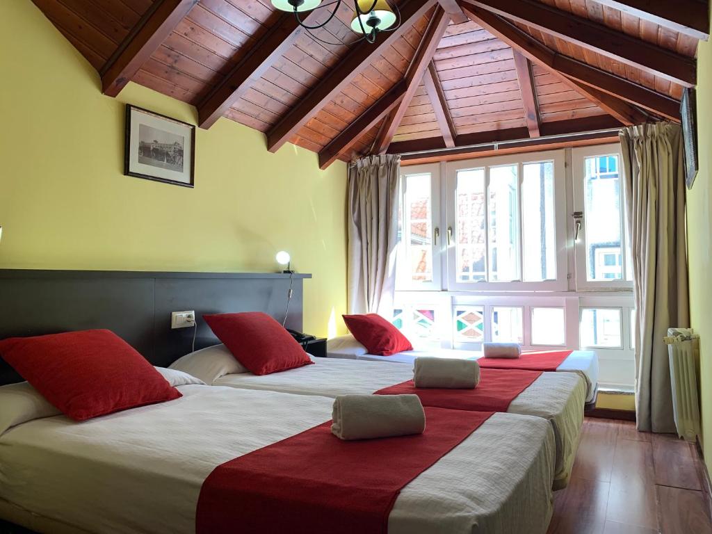 拉科鲁尼亚Hostal Hotil Coruña Centro的两间带红色枕头的酒店客房
