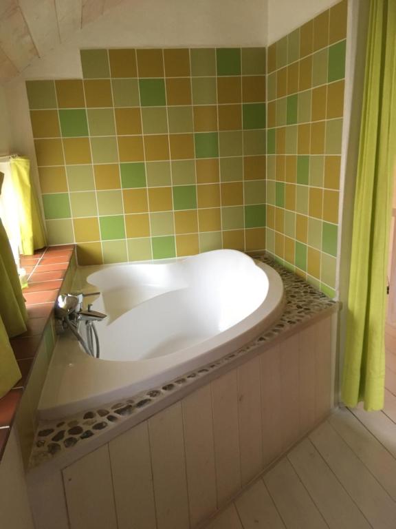 Zottegem米勒度假屋的浴室设有浴缸,铺有绿色和橙色瓷砖。