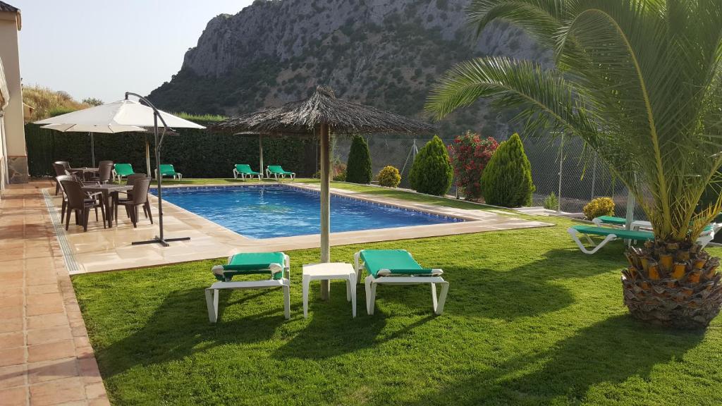 贝瑙汉Casitas Cueva del Gato的后院设有带椅子和遮阳伞的游泳池
