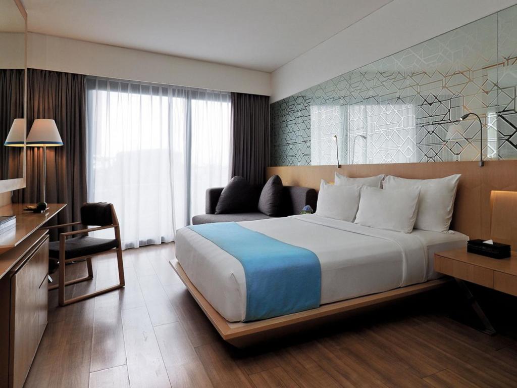 塞米亚克IZE Seminyak by LifestyleRetreats的酒店客房设有一张大床和一张书桌。