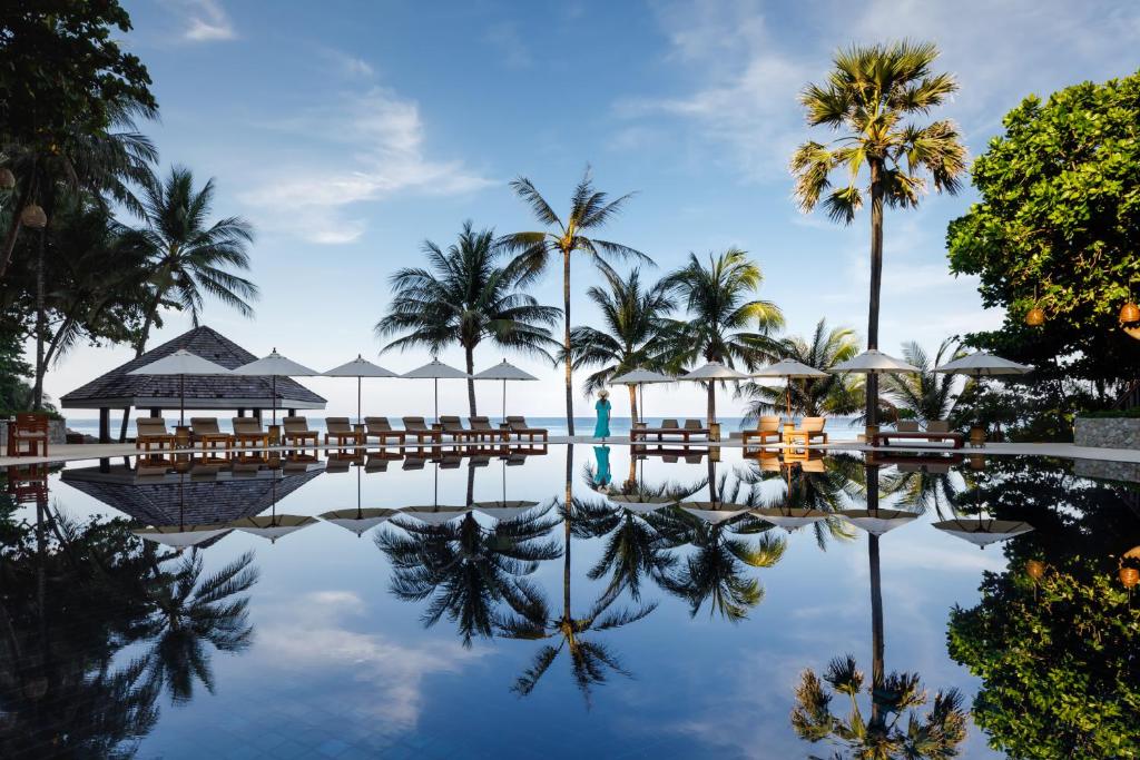 苏林海滩The Surin Phuket - SHA Extra Plus的度假村的游泳池,种植了棕榈树,配有椅子