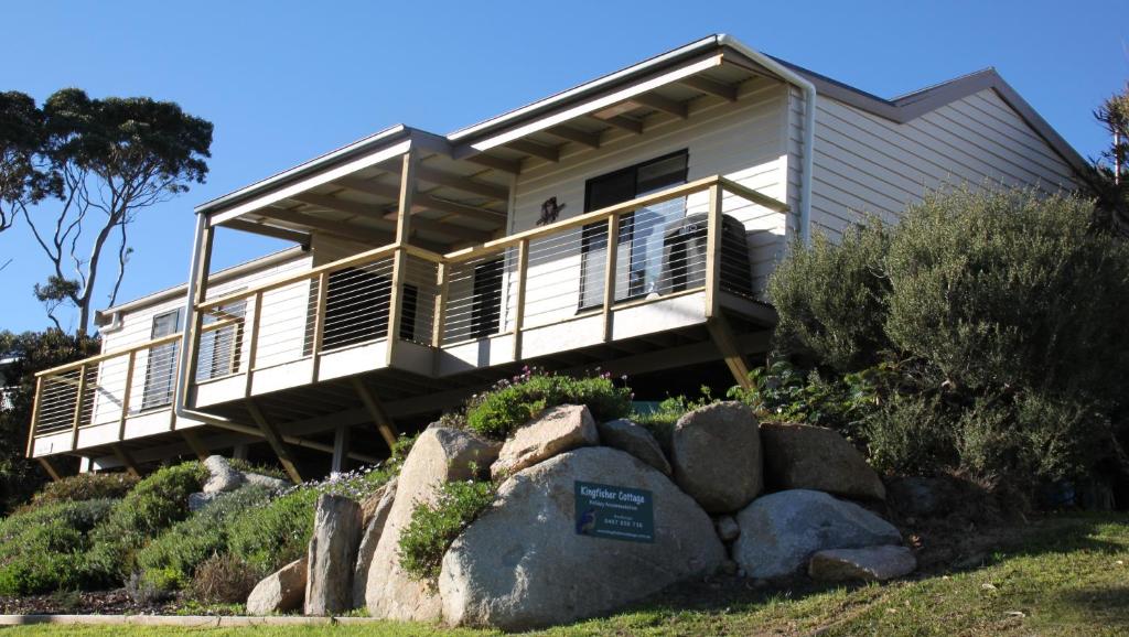 比那隆湾KINGFISHER COTTAGE Beachfront at the Binalong Bay的坐在岩石顶上的房屋