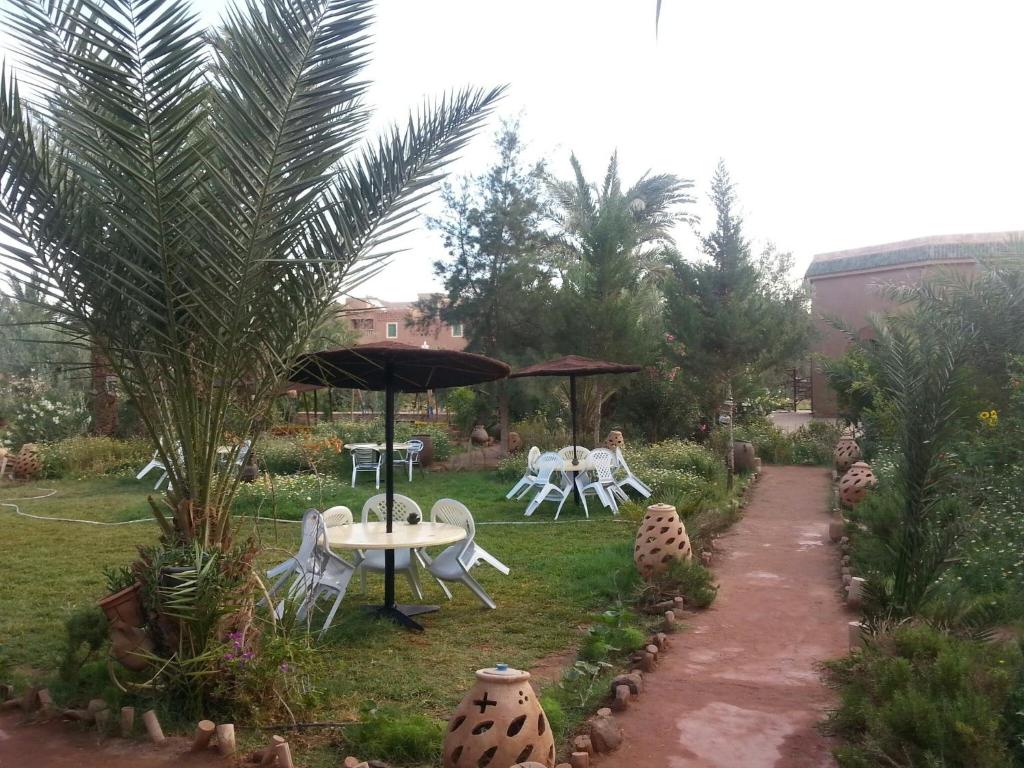 Tamgroutd'hôte Jnane-Dar Diafa的花园配有桌椅和遮阳伞。