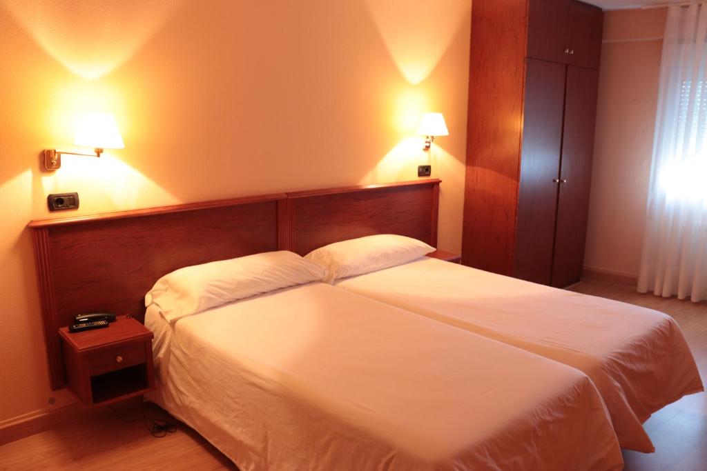 拉科鲁尼亚麦卡酒店的卧室配有一张带两个枕头的大白色床