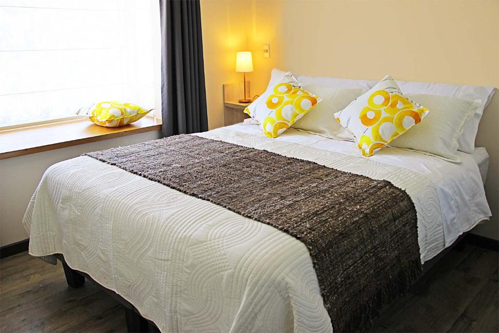巴拉斯港Departamentos Nómades del Lago的一间卧室配有一张带黄色和白色枕头的大床