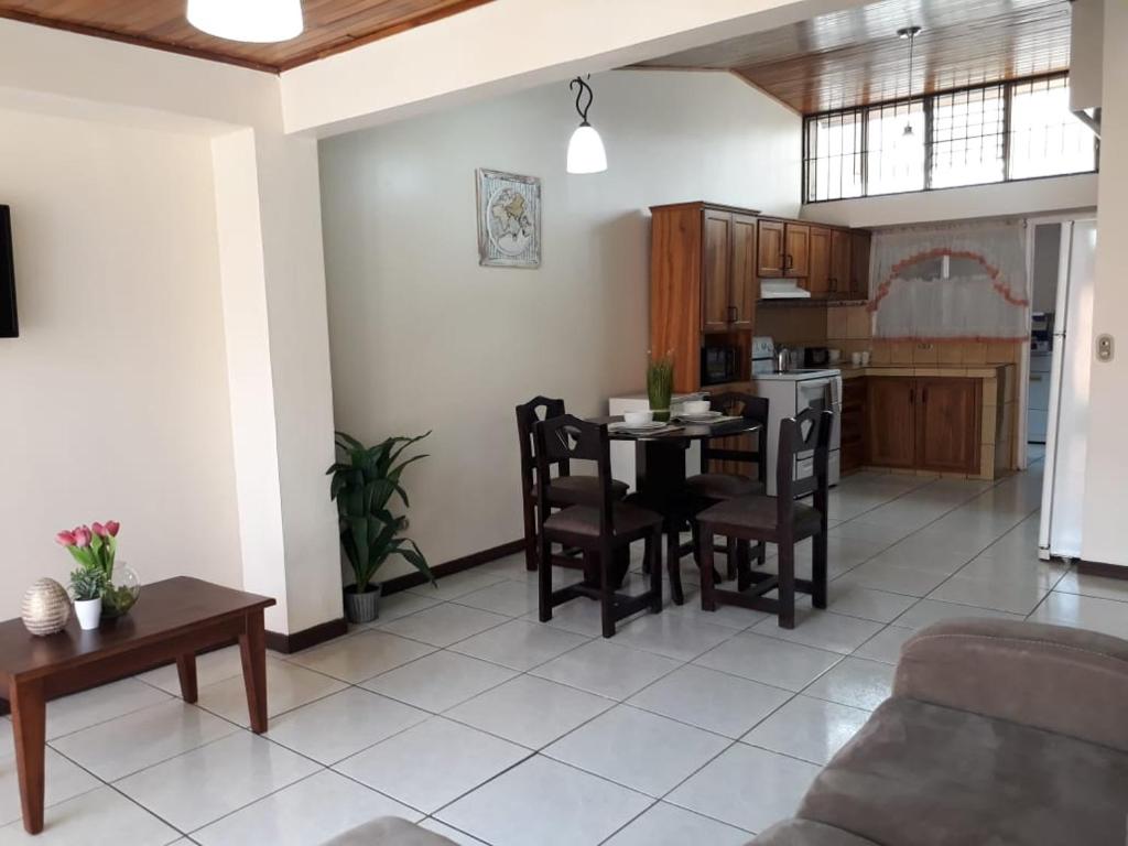阿拉胡埃拉Kubo Apartment的厨房以及带桌椅的起居室。