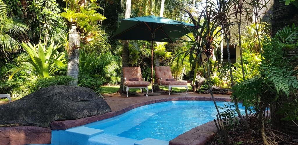 圣卢西亚非洲氛围旅馆的游泳池配有遮阳伞和两把椅子,桌子配有遮阳伞
