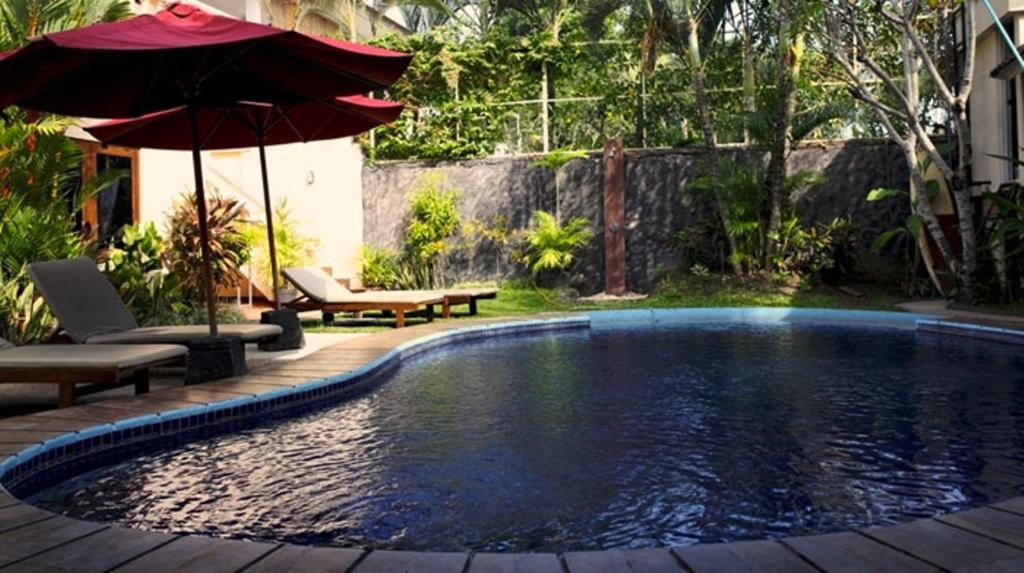塞米亚克尼拉玛雅别墅酒店的一个带遮阳伞和桌椅的游泳池