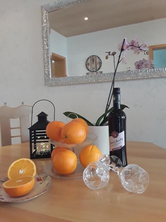 茨魏布肯Ferienwohnung Wagner的一张带橘子的桌子和一瓶葡萄酒