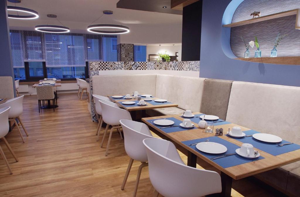 肯普滕Hotel Peterhof - urban lifestyle Kempten的用餐室配有木桌和白色椅子