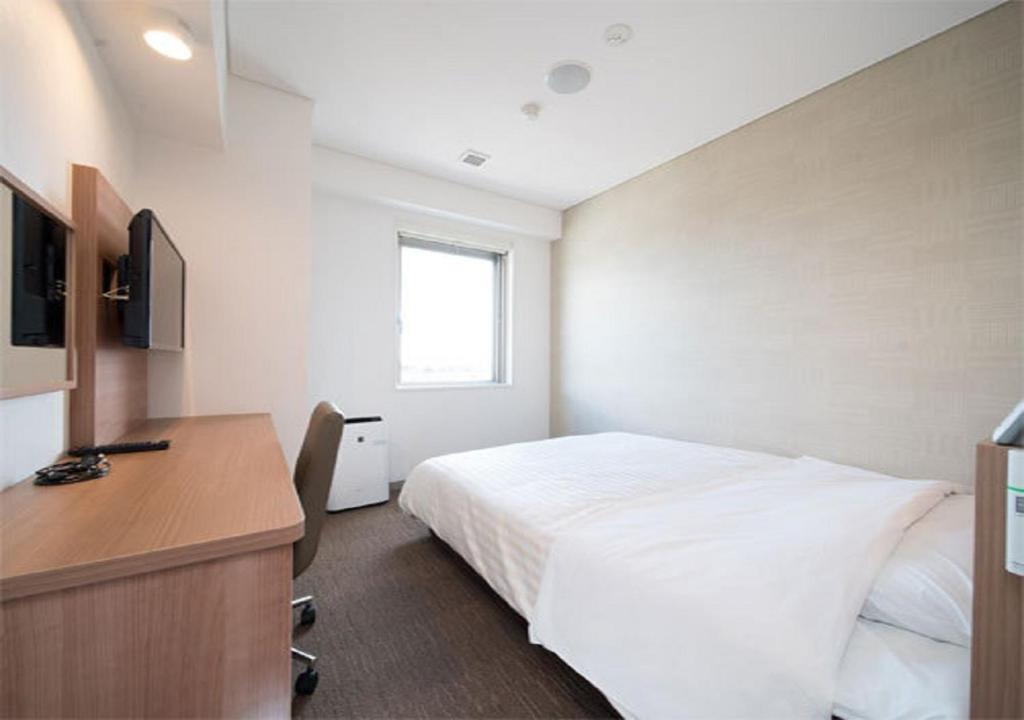 磐城Iwaki - Hotel / Vacation STAY 22975的一间卧室配有一张床、一张书桌和一台电视