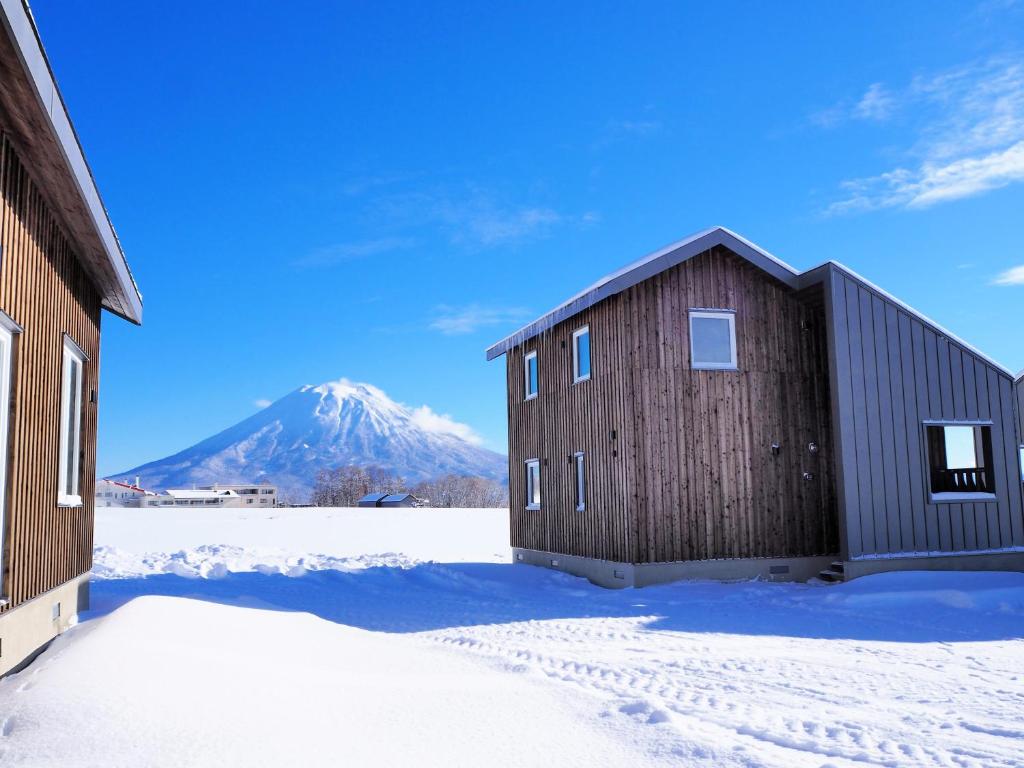 二世古Niseko Highland Cottages的雪谷仓,山底下