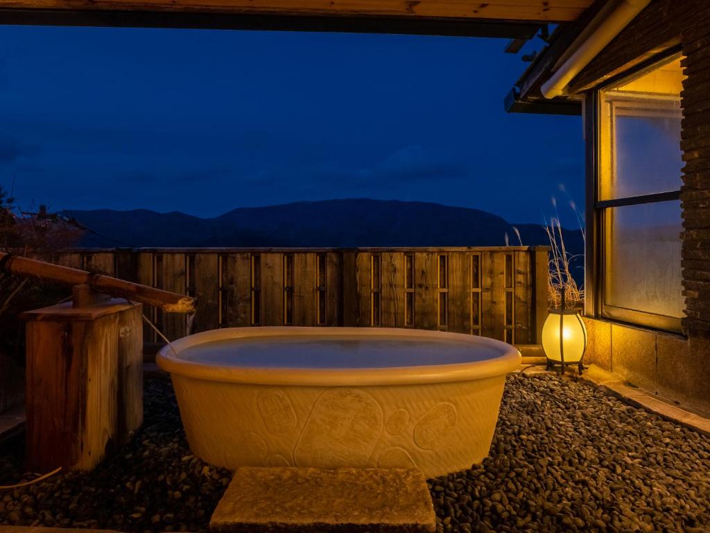 箱根箱根强罗亚麻代雅温泉日式旅馆的夜间坐在房子外的大浴缸