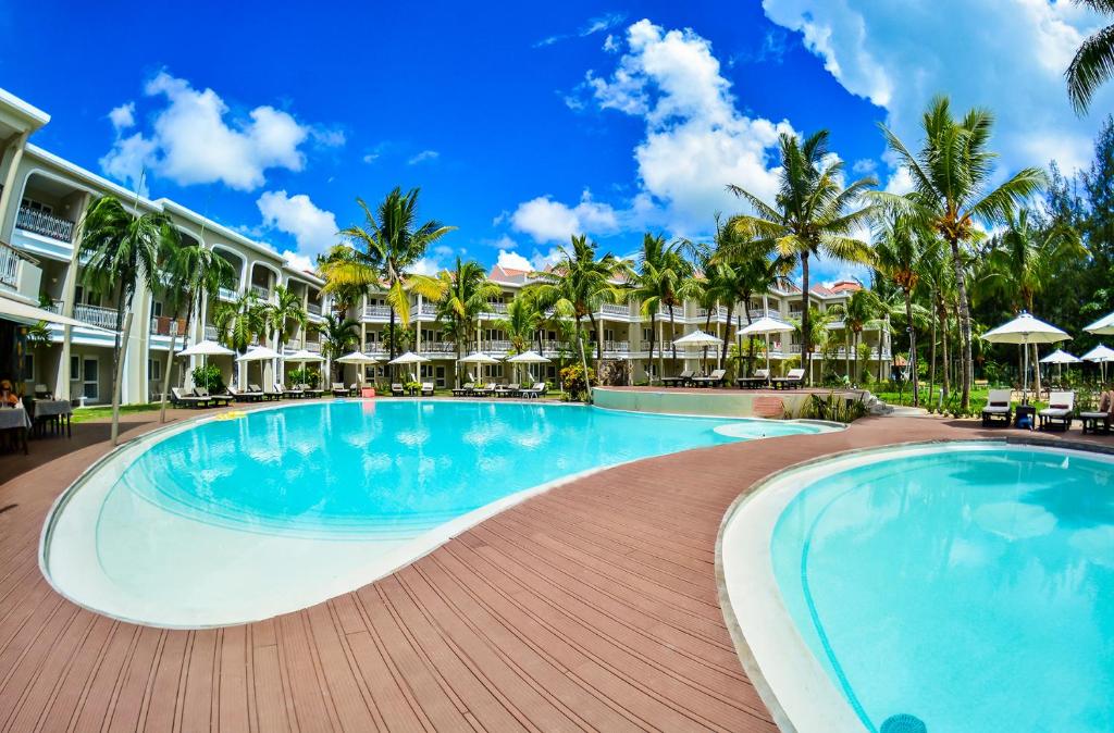 蒙舒瓦西Tarisa Resort & Spa的棕榈树和遮阳伞度假村的游泳池