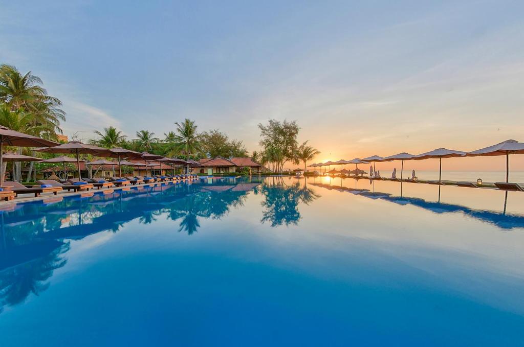 美奈海马Spa度假酒店的度假村的游泳池配有椅子和遮阳伞