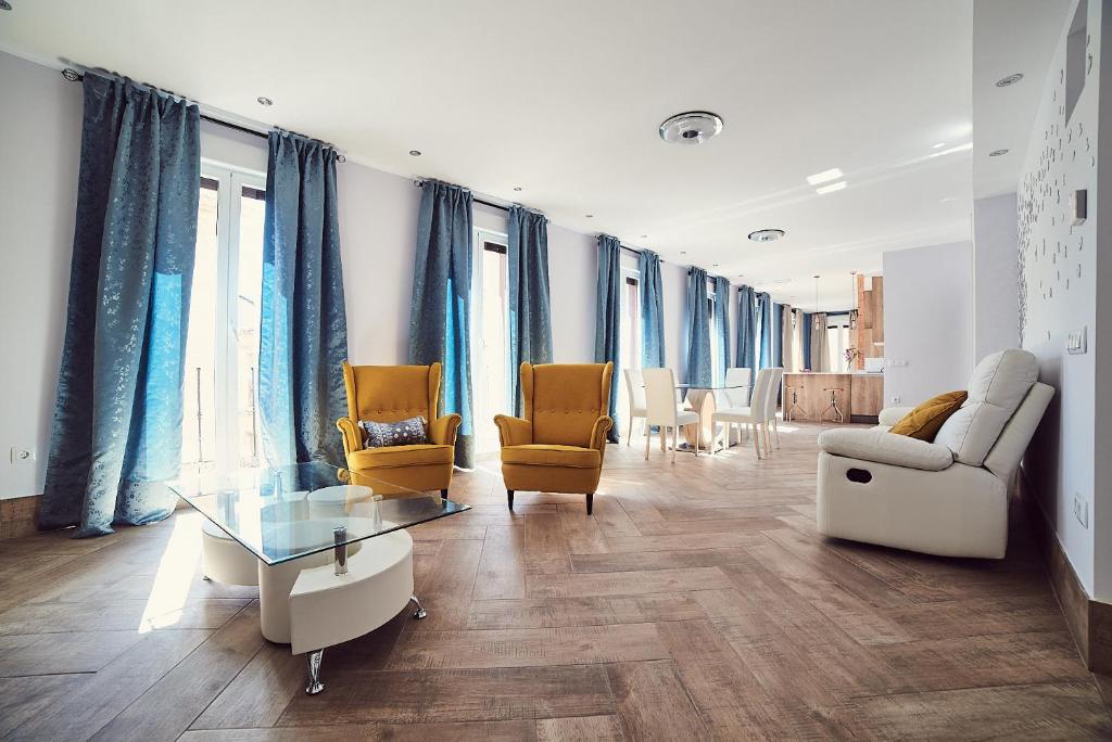托莱多La Balconada de Toledo - PARKING GRATIS - 2 HABITACIONES的客厅配有蓝色窗帘和桌椅