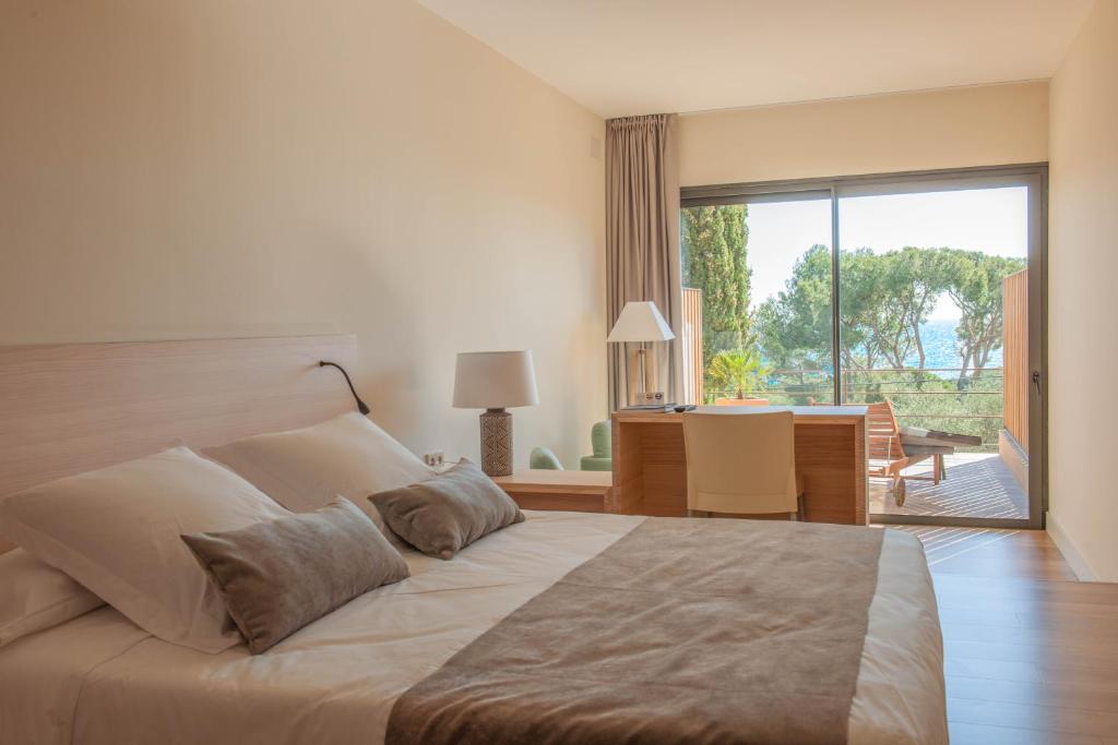 巴古尔L'Aixart Aiguablava Hotel的一间卧室配有一张大床和一张带窗户的书桌