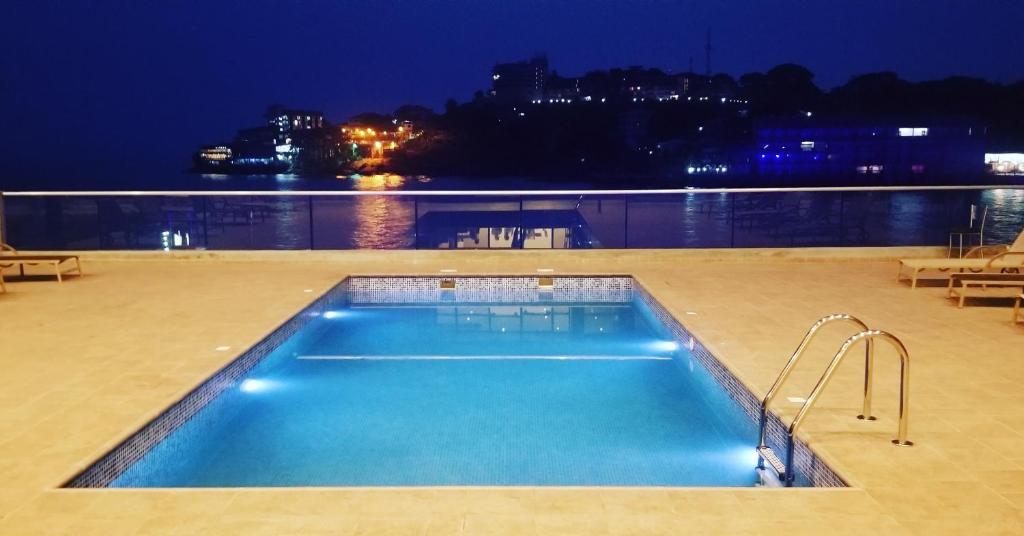 弗里敦Mamba Point Hotel的享有水景的游泳池(晚上)