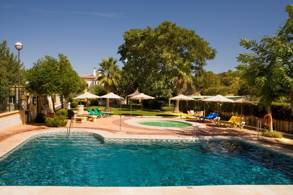 赫雷斯-德拉弗龙特拉拉库埃瓦公园酒店的一个带椅子和遮阳伞的大型游泳池