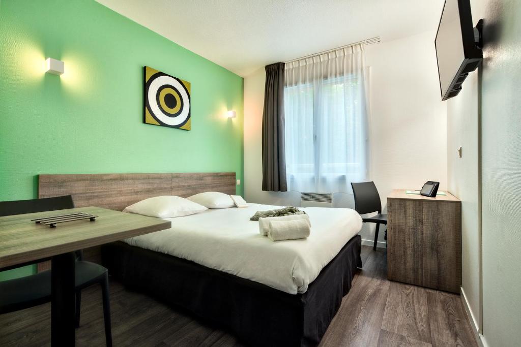 图卢兹图卢兹大都会泽尼图德公寓式酒店的酒店客房设有一张大床和一张书桌。