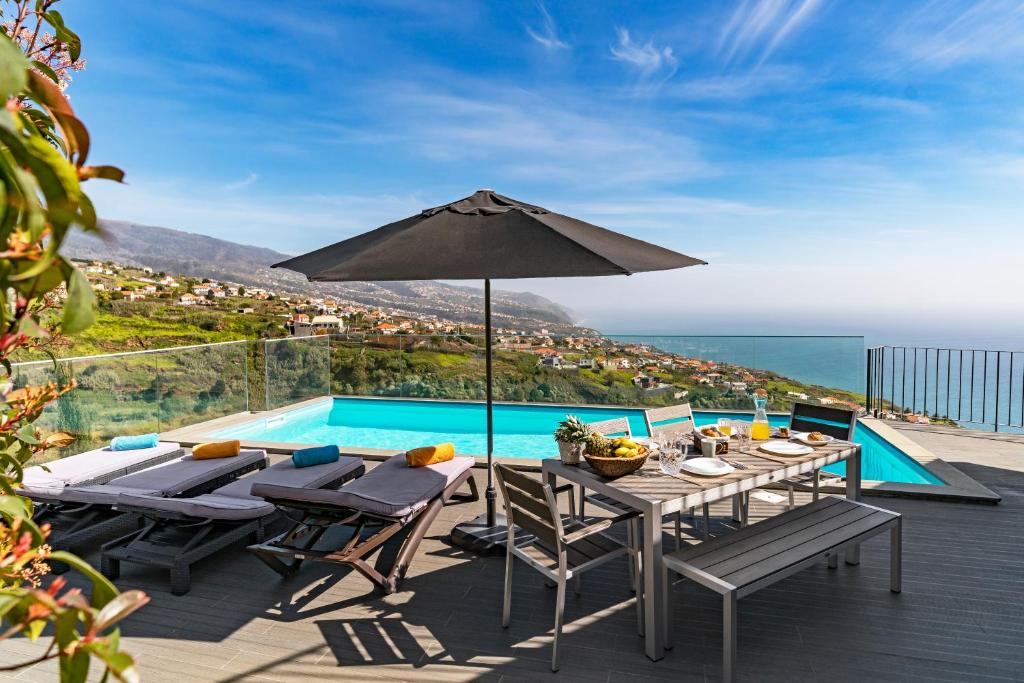 普拉泽里什Villa Clementina | Cliffs&Ocean | Heated Pool的庭院设有带遮阳伞的桌子和游泳池。