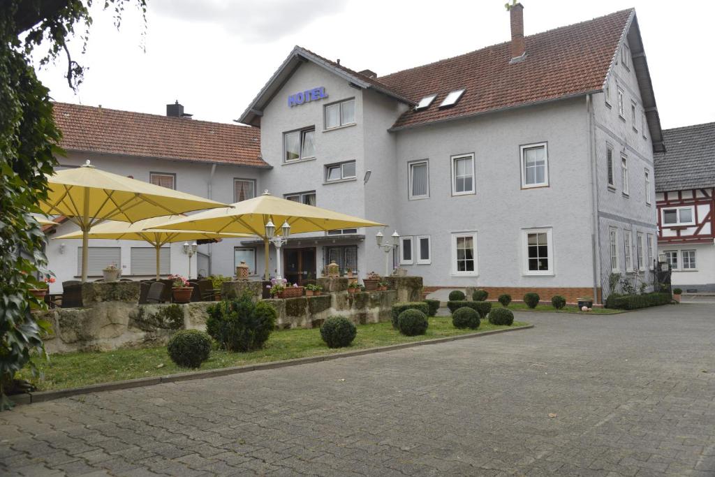 诺伊基兴Hotel Zur Stadt Cassel的前面设有桌子和遮阳伞的酒店