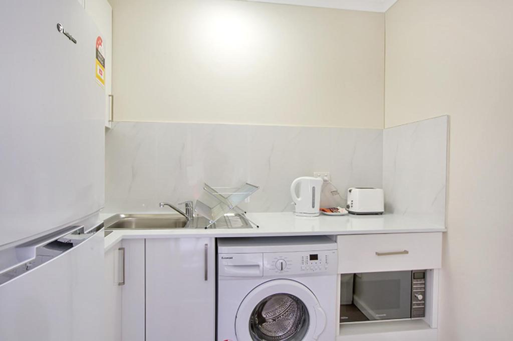 悉尼Renovated Stylish Studio的白色的厨房配有洗衣机和水槽