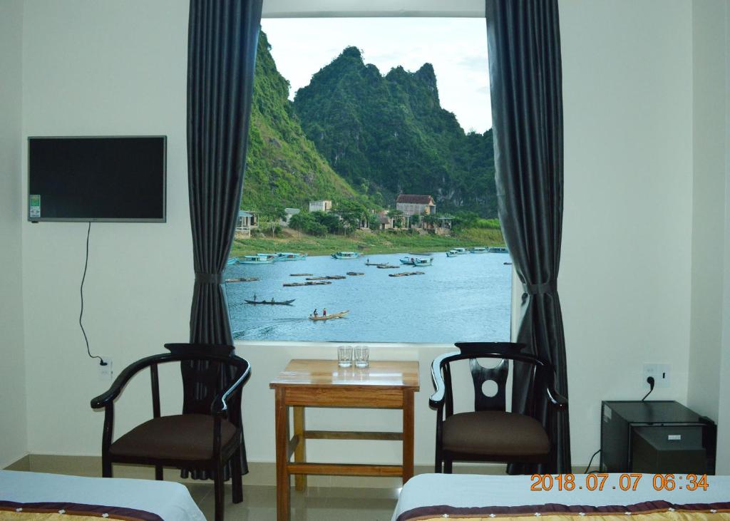 峰牙Son Doong Riverside的一间设有两把椅子的房间和一个带水中船只的窗户
