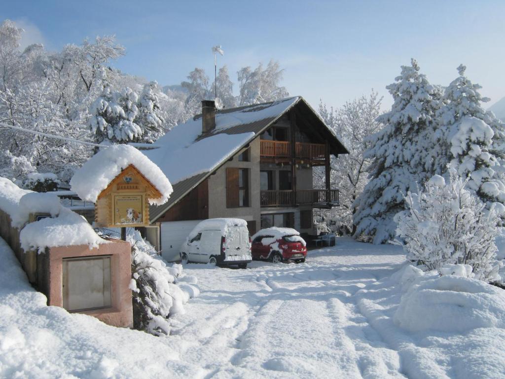 布里昂松Le Petit Randonneur的雪覆盖的房子,外面停有汽车